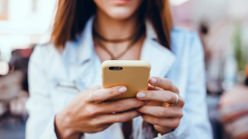 Tanara acceseaza Facebook de pe un smartphone
