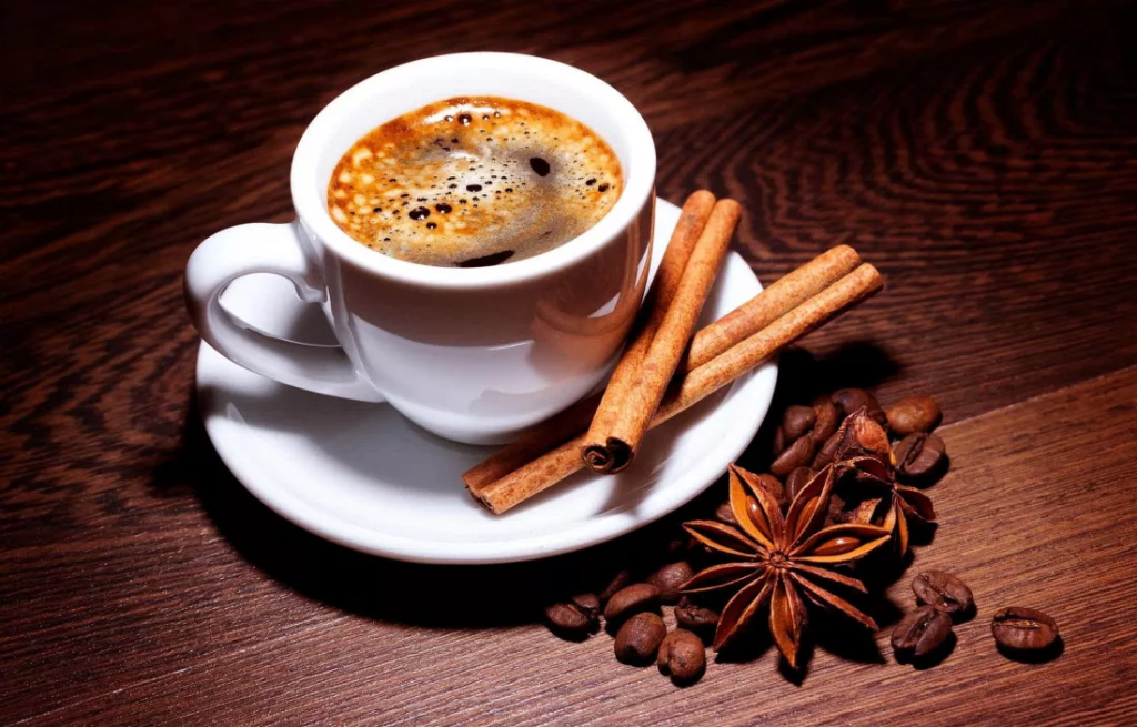 Ceasca de cafea servita alaturi de bete de scortisoara