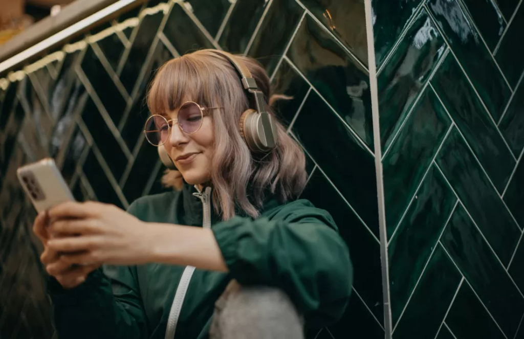 Tanara asculta muzica de pe smartphone folosind aplicatia Spotify